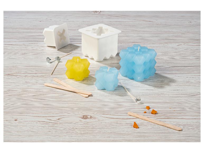 Kaarsenmaakset met blauwe en gele kaarsen, mallen en lonten op een houten tafel.