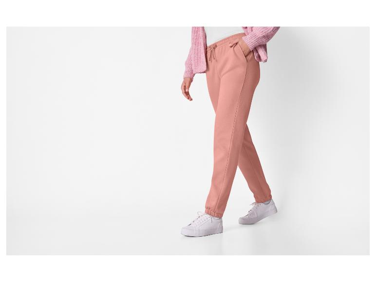 Een persoon in roze joggingbroek en een roze vest.