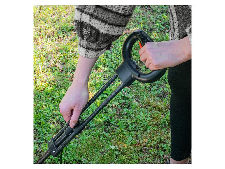 Persoon houdt een zwarte grastrimmer met oranje knop vast, klaar om het gras te trimmen.