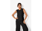 Vrouw in zwarte mouwloze top en wijde broek.