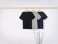 Drie T-shirts in zwart, grijs en donkerblauw hangen op een houten hanger.