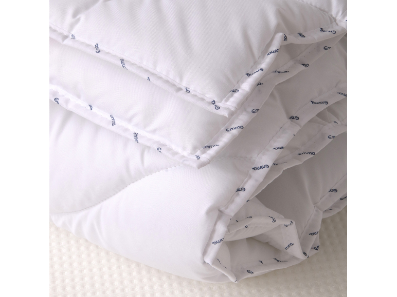 Wit gevouwen dekbed met een subtiel patroon van het woord 'Emma' in blauw.