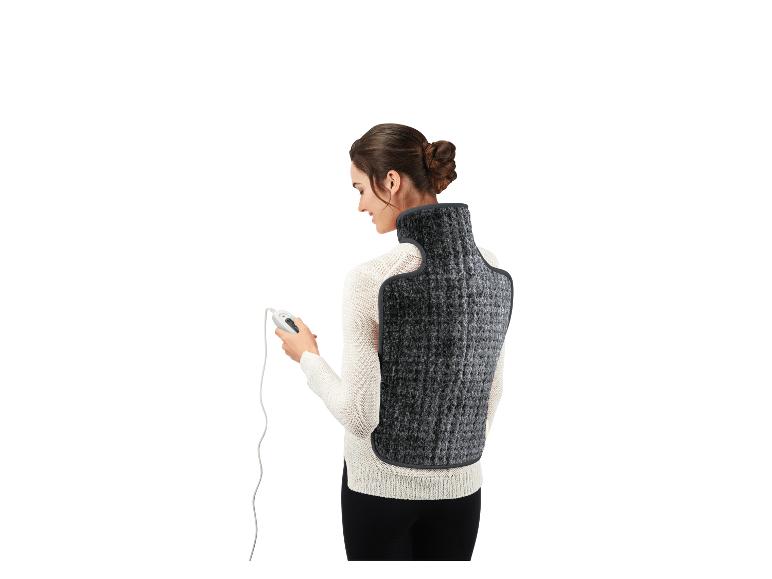 Vrouw draagt een elektrisch rug- en nekverwarmingskussen, met afstandsbediening.