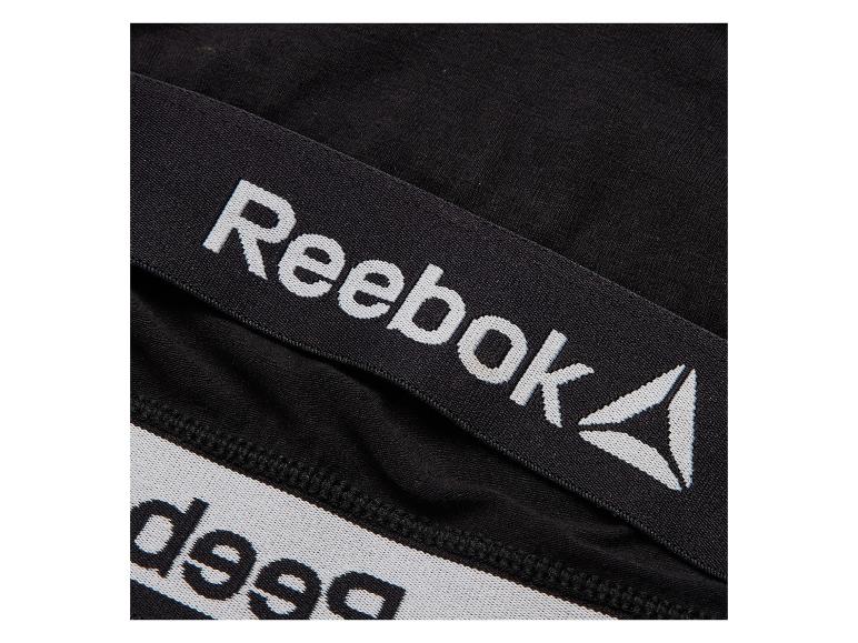 Zwarte elastische band met wit Reebok-logo en een ander gedeeltelijk zichtbaar logo.