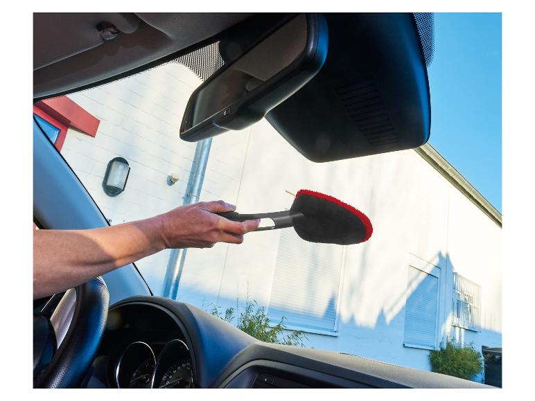 Een persoon gebruikt een borstel om de binnenkant van een auto te reinigen.