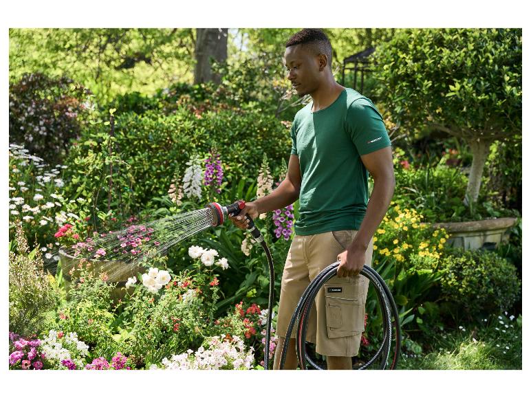 Man besproeit bloemen in een tuin met een Parkside tuinslang en spuitpistool.