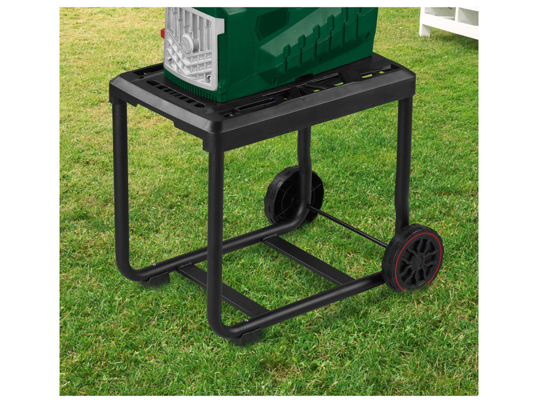 Een zwarte, metalen trolley met wielen voor een groene tuingereedschapmachine.