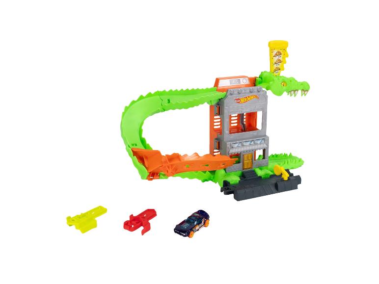 Speelgoedautobaan met een groene alligator, een gebouw en een donkerblauwe speelgoedauto.
