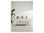 Bed met geruit beddengoed, houten hoofdbord, plant en nachtkastje met lamp.
