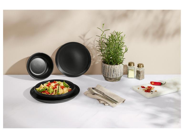 Zwarte borden met pasta, rozemarijn, zout en peper, chilipepers op marmeren plank.