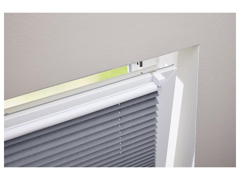 Grijze plisségordijnen gemonteerd in een dakraam.