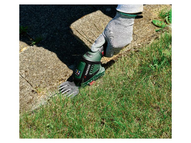 Gehandschoende hand gebruikt Parkside accugrasschaar om gras te trimmen
