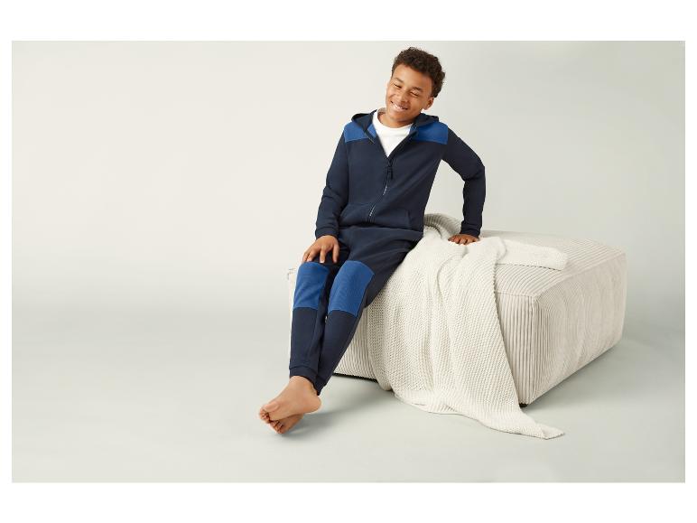 Een jongen draagt een blauwe hoodie en joggingbroek.