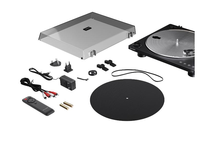 Zwarte platenspeler met transparante hoes, afstandsbediening en accessoires op witte achtergrond.