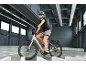 Vrouw op elektrische fiets met helm en zonnebril in een garage.