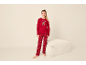 Meisje in rode kerstpyjama met teddybeerprint, staand naast een witte poef