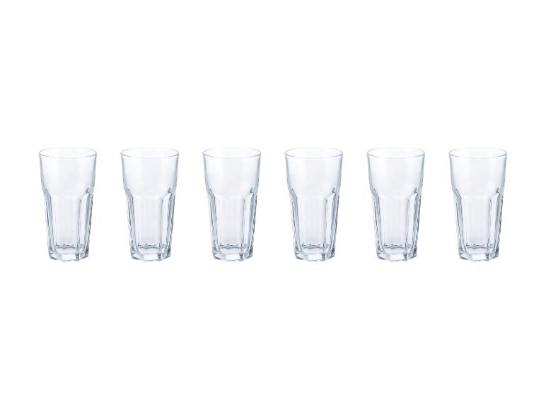 Zes lege, transparante waterglazen, op een rij op een witte achtergrond.