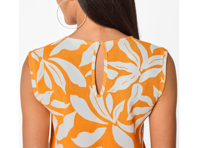 Rug van een vrouw in een oranje top met witte bloemenprint en een uitsnede.
