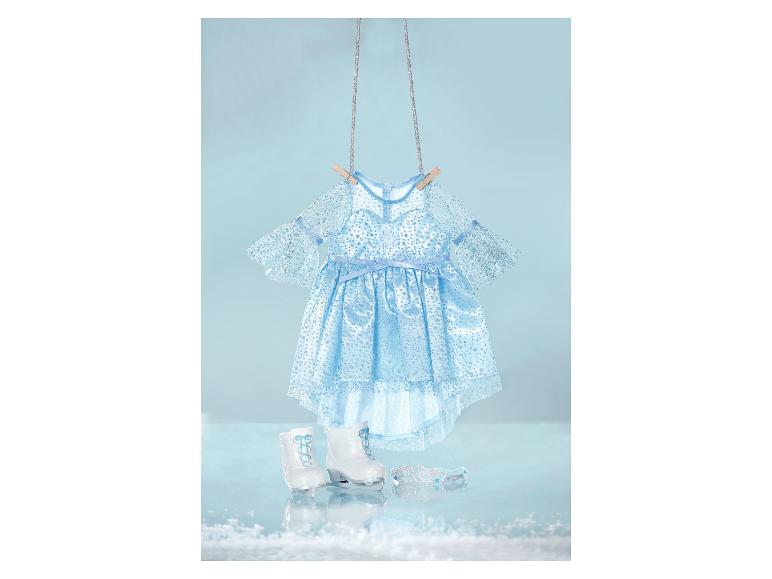 Blauwe glitterjurk, witte schaatsen en tiara voor poppen, hangend tegen een lichtblauwe achtergrond.