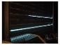 LED-stripverlichting op een donkere houten schutting, reflecterend op de grilldeksel.