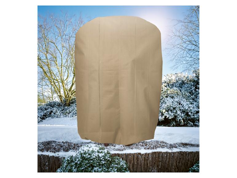 Een beige plantenhoes in een besneeuwd winterlandschap.