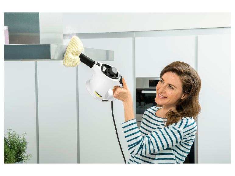 Vrouw reinigt afzuigkap met een handstoomreiniger, glimlachend.