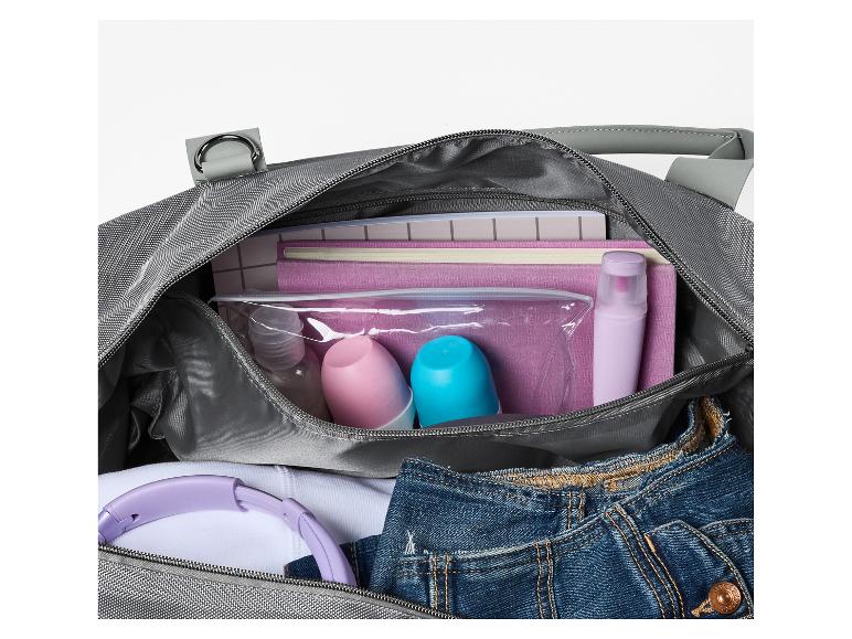 Lichtgrijze reistas met toiletartikelen, koptelefoon en jeans.