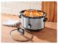 Slowcooker met kip op een houten aanrecht in de keuken.