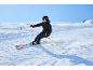 Vrouw in zwarte ski-jas en skibroek skiet van een besneeuwde helling.
