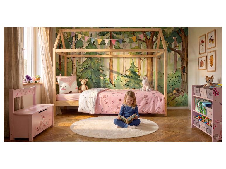 Kinderkamer met bosthema, houten bed, roze meubels en een lezend meisje.