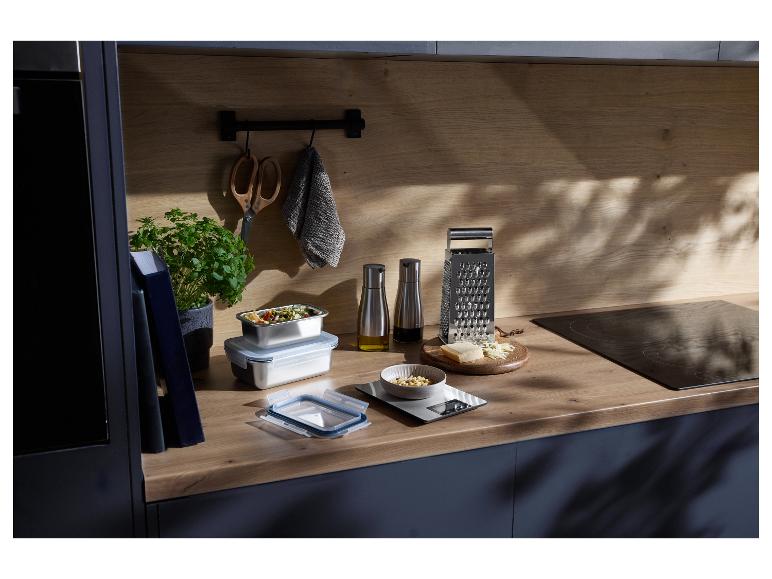 Keukenblad met voedselcontainers, kaasschaaf, keukenweegschaal en kruiden.