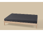 Een houten bedframe met een donkergrijs hoeslaken op een lichte achtergrond.