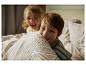Twee kinderen spelen in bed met gestreepte dekbedovertrekken.
