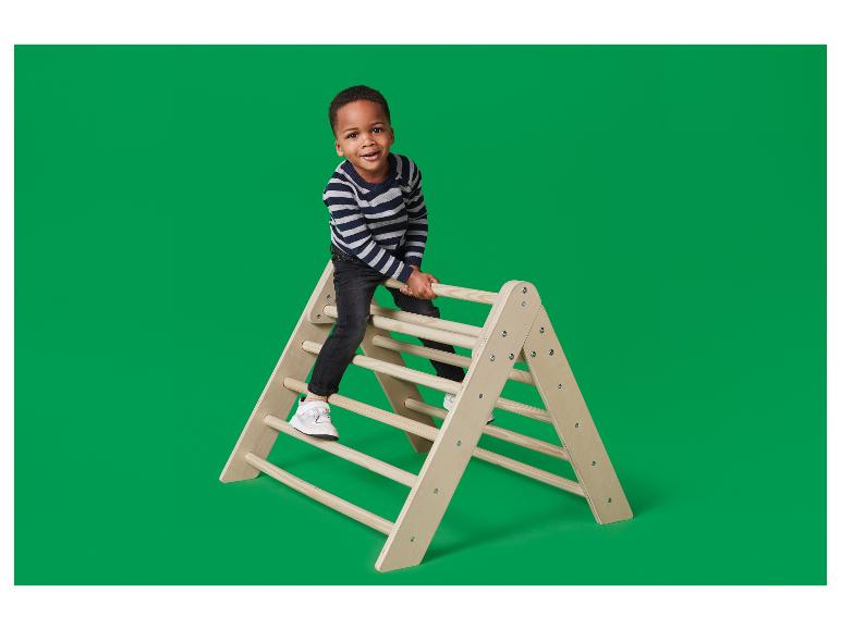 Een blije jongen klimt op een houten driehoekig klimrek.