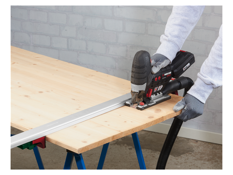 Een persoon gebruikt een Parkside decoupeerzaag om hout te zagen op een werktafel.