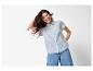 Lachende vrouw in blauw overhemd en jeans