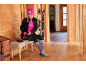 Vrouw maakt zich klaar om te skiën, draagt een roze muts, zwarte jas, roze shirt, zwarte broek en grijze sokken.