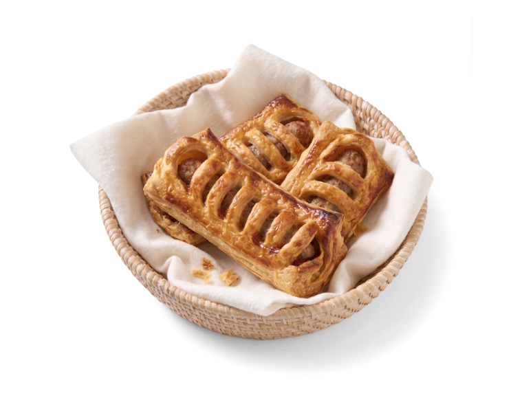 Drie goudbruine worstenbroodjes in een mandje met een servet.
