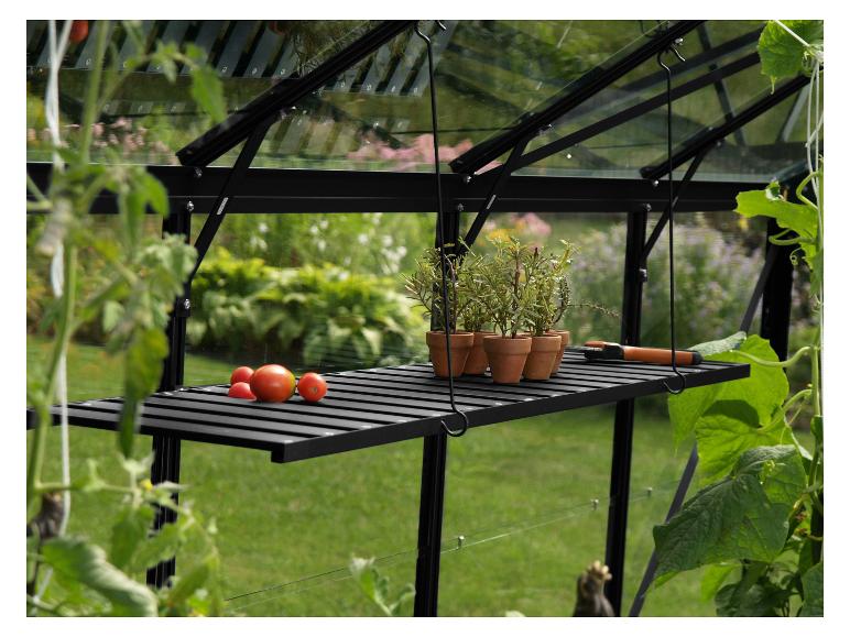 Een zwarte metalen tuinkas met een houten plank en potplanten