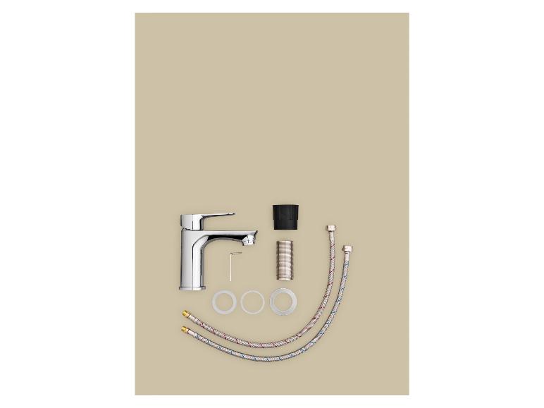 Badkamerkraanset met zilveren kraan, flexibele slangen en accessoires op een beige achtergrond.