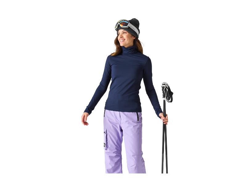 Vrouwelijke skiër in muts, skibril, coltrui en skibroek.