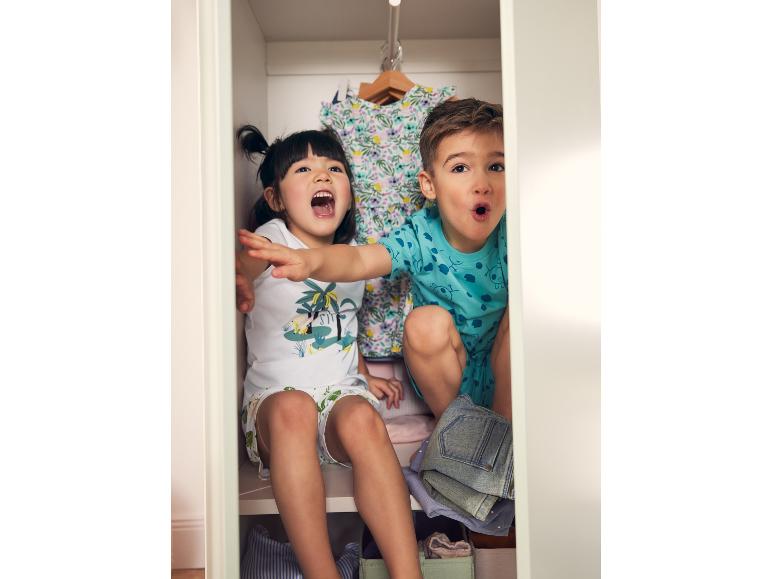 Kinderen spelen verstoppertje in een kast met zomerkleding