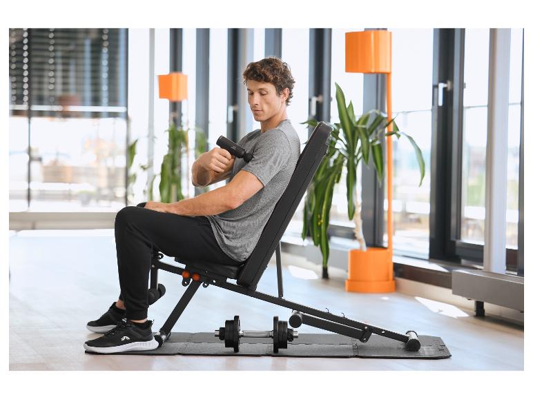 Man zit op een trainingsbank en gebruikt een CRIVIT massageapparaat op een Bodenschutzmatte.