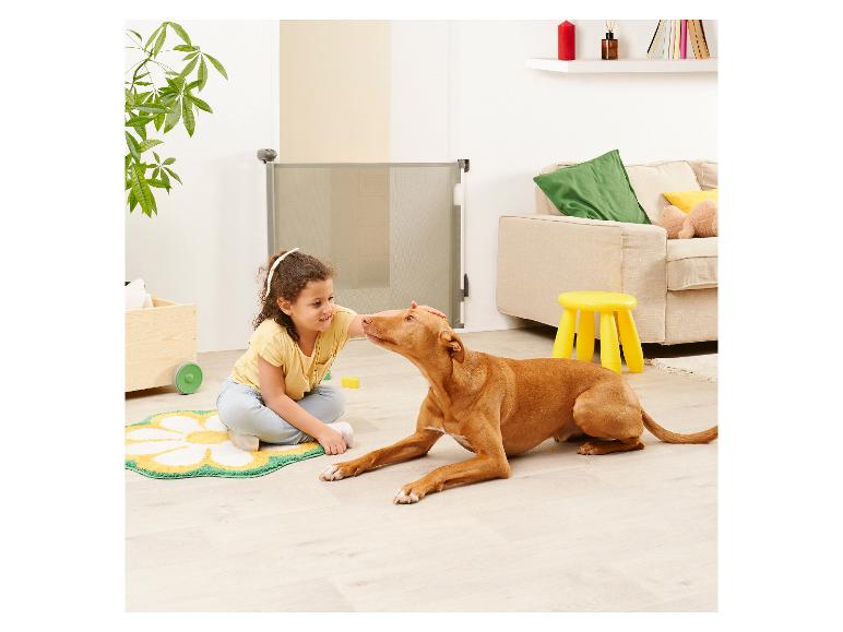 Kind aait hond bij een veiligheidshekje.