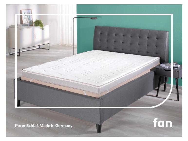 Een grijs bedframe met een wit matras en een nachtkastje.