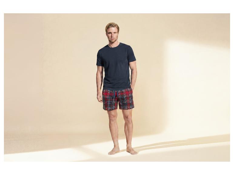 Man in donkerblauw T-shirt en rood geruite shorts.