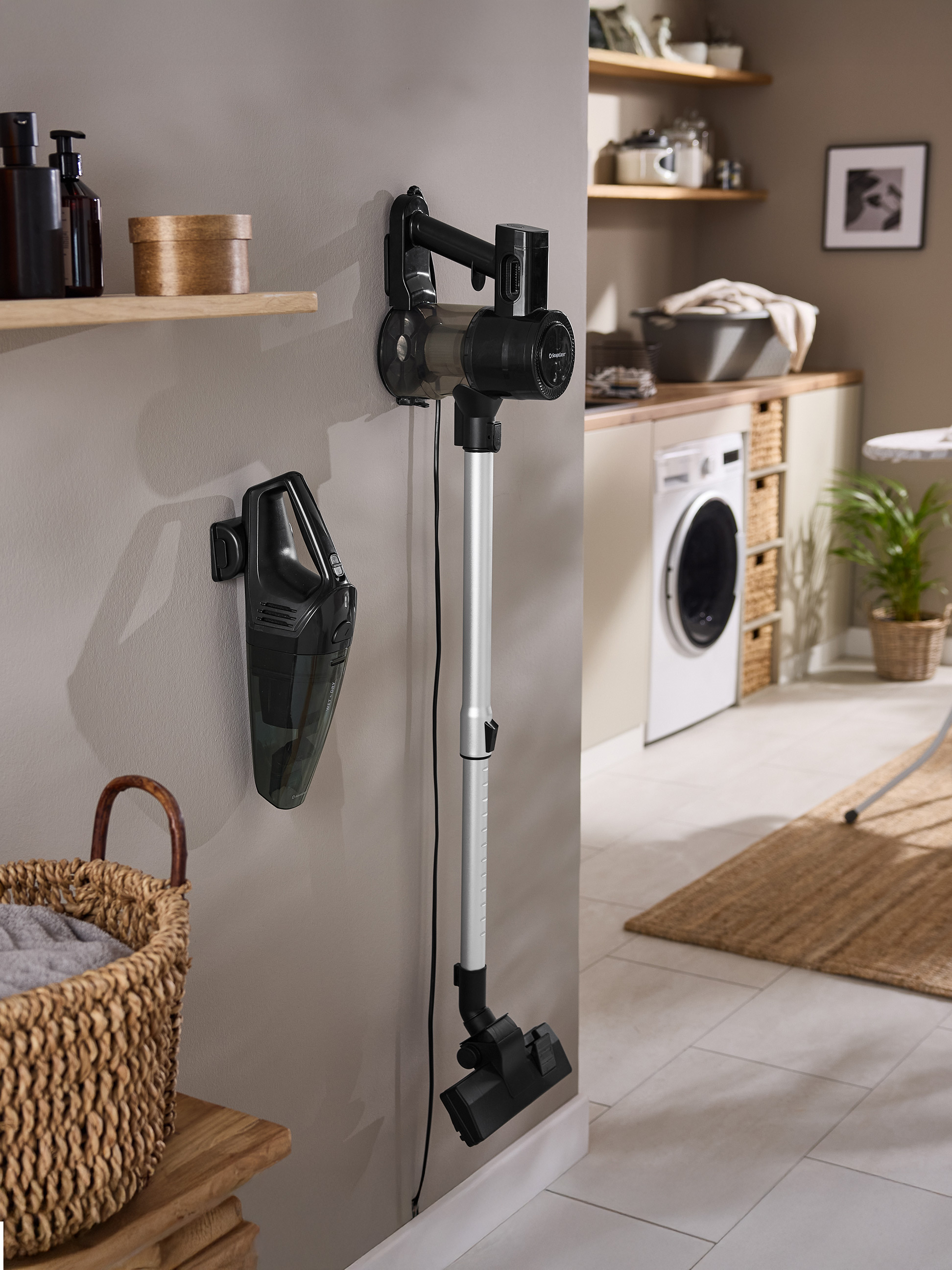 Twee SilverCrest stofzuigers, een kruimeldief en een steelstofzuiger, hangen aan de muur in een bijkeuken.