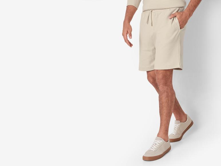 Beige shorts en casual sneakers.