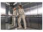 Vrouw in een beige sweatshirt en joggingbroek, staand in een lift.