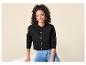 Vrouw in zwart vest en blauwe jeans, glimlachend.